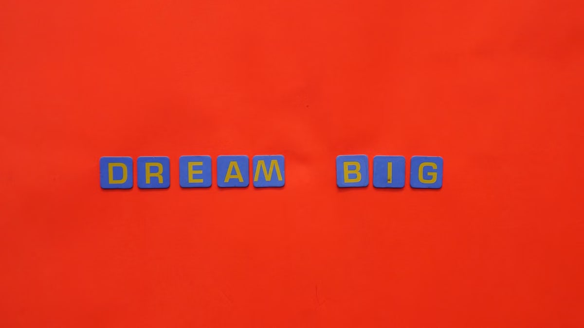 Blue tiles forming the 'Dream Big' quote against a striking red background.